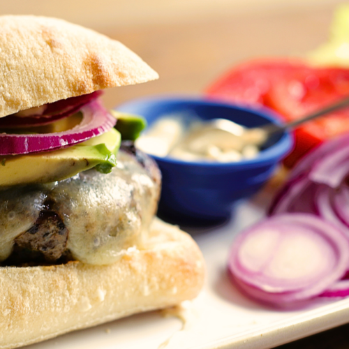 turkey burger on a plate with red onion, lettuce, tomato