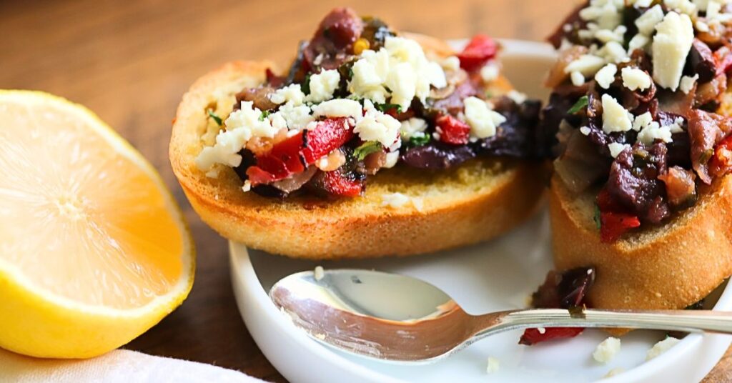 crostini with mixture and feta on top with half sliced lemon at the side